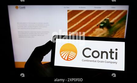 Stoccarda, Germania, 03-30-2022: Persona che tiene il cellulare con il logo della Continental Grain Company (CGC) americana sullo schermo di fronte Foto Stock