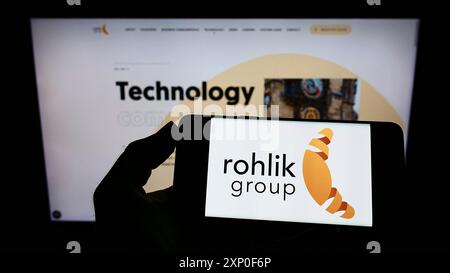 Stoccarda, Germania, 03-30-2022: Persona che detiene il cellulare con il logo della società di consegna ceca Rohlik Group a.s. sullo schermo davanti all'azienda Foto Stock