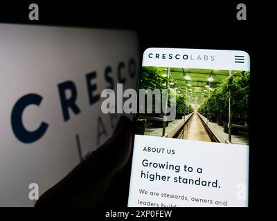 Stoccarda, Germania, 03-28-2022: Persona che detiene il cellulare con pagina web della società americana di cannabis Cresco Labs Inc. Sullo schermo davanti al logo. Concentrati Foto Stock