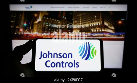 Stoccarda, Germania, 03-12-2022: Persona che possiede uno smartphone con il logo della società Johnson Controls International plc (JCI) sullo schermo di fronte a. Foto Stock