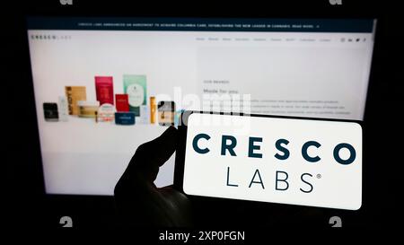 Stoccarda, Germania, 03-28-2022: Persona che detiene il cellulare con il logo della società statunitense di cannabis Cresco Labs Inc. Sullo schermo di fronte alla pagina web aziendale. Foto Stock