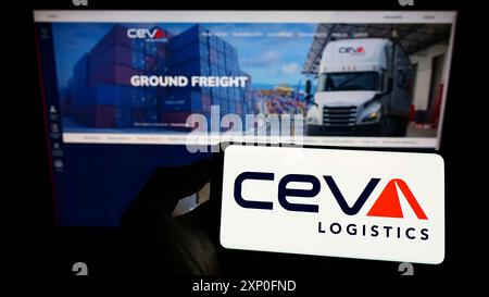 Stoccarda, Germania, 03-12-2022: Persona che detiene un cellulare con il logo della società di trasporto merci francese CEVA Logistics sullo schermo davanti alla pagina web aziendale. Foto Stock