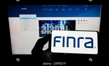 Stoccarda, Germania, 03-05-2022: Persona che detiene un cellulare con il logo della Financial Industry Regulatory Authority (FINRA) sullo schermo davanti alla pagina web. Foto Stock