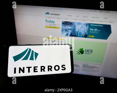 Stoccarda, Germania, 05-08-2022: Persona che detiene un telefono cellulare con il logo del conglomerato russo Interros sullo schermo di fronte alla pagina web aziendale. Concentrati Foto Stock