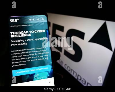 Stoccarda, Germania, 02-26-2022: Persona che detiene lo smartphone con pagina web della società di telecomunicazioni satellitari SES SA sullo schermo con logo. Concentrati su Foto Stock