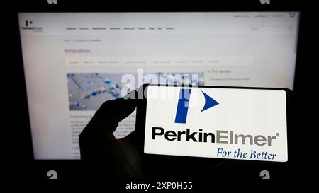 Stoccarda, Germania, 02-20-2022: Persona che tiene il cellulare con il logo della società americana di tecnologia medica PerkinElmer Inc. Sullo schermo di fronte Foto Stock