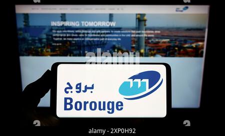 Stoccarda, Germania, 02-20-2022: Persona con smartphone con logo del produttore arabo di polimeri Borouge Group sullo schermo davanti al sito web. Foto Stock