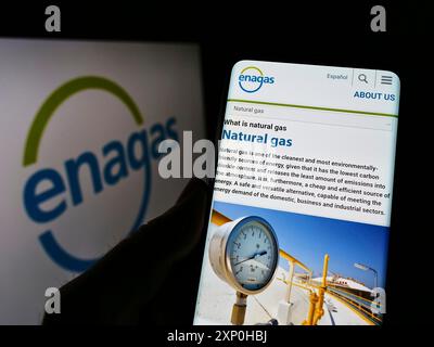 Stoccarda, Germania, 02-13-2022: Persona che detiene il cellulare con pagina web della società spagnola di distribuzione del gas Enagas SA sullo schermo con il logo. Concentrati su Foto Stock