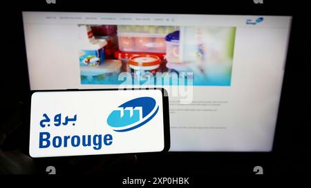 Stoccarda, Germania, 02-20-2022: Persona che tiene il cellulare con il logo del produttore arabo di polimeri Borouge Group sullo schermo di fronte all'azienda Foto Stock