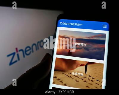 Stoccarda, Germania, 02-13-2022: Persona che detiene uno smartphone con sito web della società cinese Zhenro Properties Group Limited sullo schermo con logo. Concentrati Foto Stock