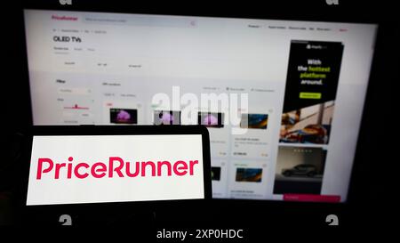 Stoccarda, Germania, 02-13-2022: Persona che detiene il cellulare con il logo della società svedese Pricerunner International AB sullo schermo davanti all'azienda Foto Stock