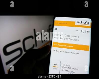 Stoccarda, Germania, 02-13-2022: Persona che detiene lo smartphone con weboage della società tedesca di protezione del credito Schufa Holding AG sullo schermo con logo. Foto Stock