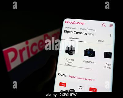Stoccarda, Germania, 02-13-2022: Persona che detiene il cellulare con pagina web della società svedese Pricerunner International AB sullo schermo davanti al logo. Foto Stock