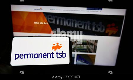 Stoccarda, Germania, 02-06-2022: Persona che detiene un cellulare con il logo della società irlandese Permanent TSB Group Holdings plc sullo schermo di fronte alla pagina web. Foto Stock