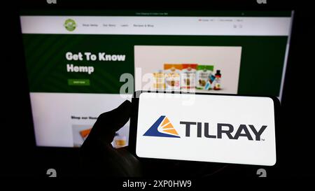 Stoccarda, Germania, 02-06-2022: Persona che tiene il cellulare con il logo della società canadese di cannabis Tilray Inc. Sullo schermo di fronte alla pagina web aziendale. Foto Stock