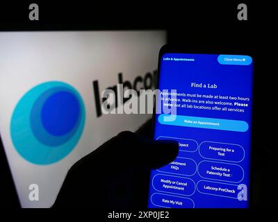 Stoccarda, Germania, 01-30-2022: Persona che detiene il cellulare con pagina web della società di laboratorio statunitense Labcorp sullo schermo davanti al logo aziendale. Concentrati su Foto Stock