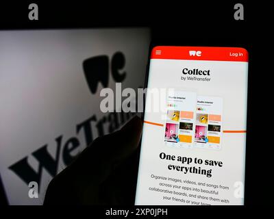 Stoccarda, Germania, 01-28-2022: Persona che possiede uno smartphone con pagina web della società olandese di condivisione file WeTransfer B.V. sullo schermo davanti al logo. Foto Stock