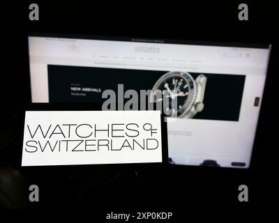 Stoccarda, Germania, 01-16-2022: Persona che tiene il cellulare con il logo del rivenditore britannico Watches of Switzerland Group PLC sullo schermo di fronte Foto Stock