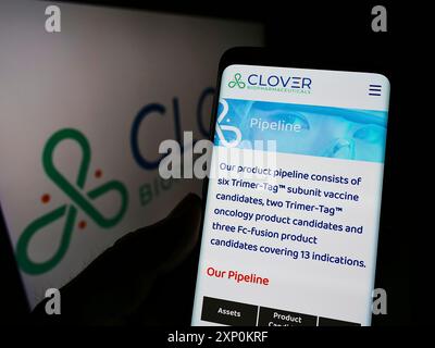 Stoccarda, Germania, 01-09-2022: Persona che detiene lo smartphone con pagina web della società cinese Clover Biopharmaceuticals Ltd. Sullo schermo con logo. Concentrati Foto Stock