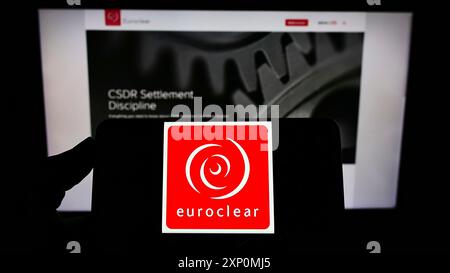 Stoccarda, Germania, 01-06-2022: Persona che detiene il cellulare con il logo della società finanziaria belga Euroclear Group sullo schermo davanti all'azienda Foto Stock