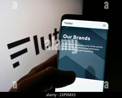 Stoccarda, Germania, 01-06-2022: Persona che detiene lo smartphone con pagina web della società di libraio irlandese Flutter Entertainment plc sullo schermo con logo. Foto Stock