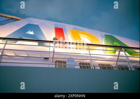 Logo AIDA bella illuminato attaccato a una nave da crociera AIDA durante il cielo nuvoloso, vista dall'angolo basso Foto Stock