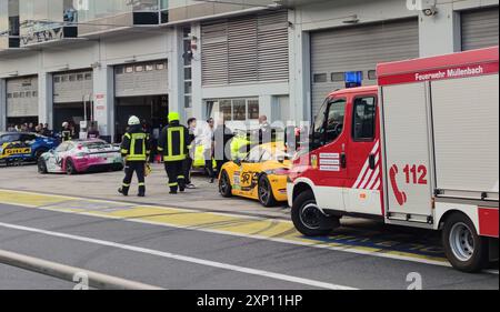 2 agosto 2024, Renania-Palatinato, Nürburg: I vigili del fuoco corrono davanti al pit 27 nella corsia dei box del Nürburgring. Un certo numero di persone è rimasto ferito quando un cilindro di aria compressa è esploso dietro i pozzetti nell'area del paddock. L'aria compressa proveniente dai cilindri viene utilizzata, tra le altre cose, per sollevare rapidamente le auto da corsa, ad esempio durante un pit stop per sostituire gli pneumatici. (Ripetizione con sezione immagine modificata) foto: Sönke Brederlow/dpa Foto Stock