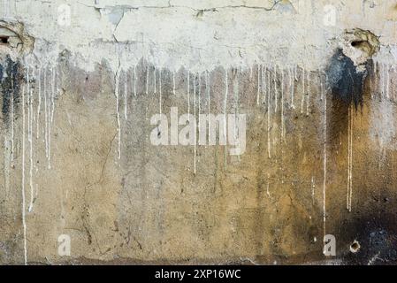 Consistenza della parete gialla rotta sporca con perdite di vernice bianca Foto Stock