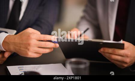 Un team di due professionisti impegnati che lavorano insieme utilizzando un rapporto e esaminando i documenti. Un dirigente che spiega la strategia di progetto online dell'azienda Foto Stock