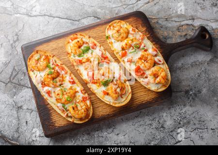 Aprire panini al forno con gamberetti, formaggio, aglio e pomodori da vicino su un tavolo di legno. Vista dall'alto orizzontale Foto Stock