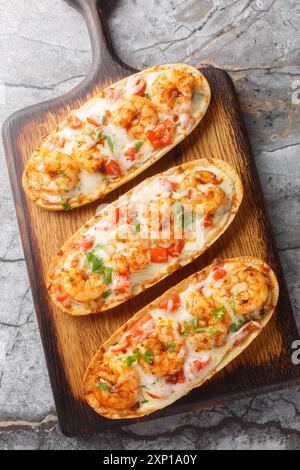 Panini caldi al forno con gamberetti, formaggio, aglio e pomodori da vicino su un tavolo di legno sul tavolo. Vista dall'alto verticale Foto Stock