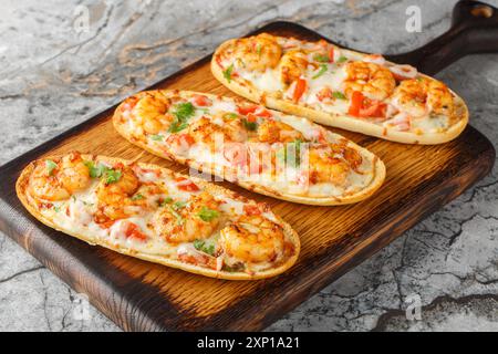 Aprire panini al forno con gamberetti, formaggio, aglio e pomodori da vicino su un tavolo di legno. Orizzontale Foto Stock