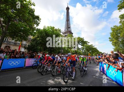 I motociclisti passano davanti alla Torre Eiffel vicino all'inizio della gara maschile su strada l'ottavo giorno dei Giochi Olimpici di Parigi del 2024 in Francia. Data foto: Sabato 3 agosto 2024. Foto Stock