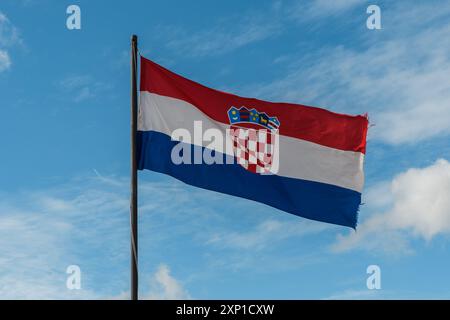 Orgoglio croato: Bandiera nazionale ondeggia contro il cielo blu Foto Stock