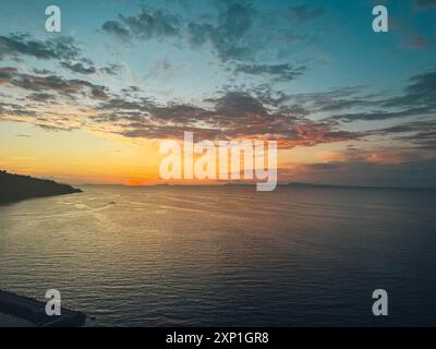 Il cielo è di un bellissimo colore arancione e rosa. L'acqua è calma e il sole sta tramontando Foto Stock