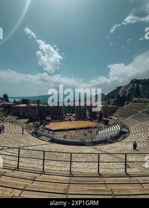 Una grande folla di persone è riunita in una grande area aperta, con un palco al centro. Il cielo è nuvoloso, ma il sole splende ancora. L'AT Foto Stock