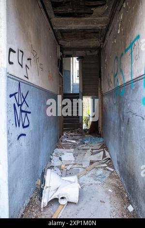 Corridoio e scalinate abbandonati e abbandonati in un edificio residenziale a Clune Park, Port Glasgow. Graffiti sul muro e toilette rotta. Foto Stock