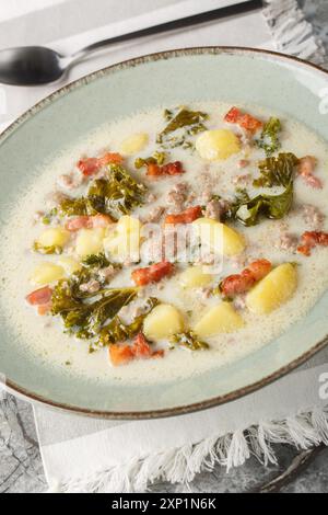 Zuppa toscana preparata con salsicce italiane, cavolo, patate, cipolla e aglio in primo piano sul piatto del tavolo. Verticale Foto Stock