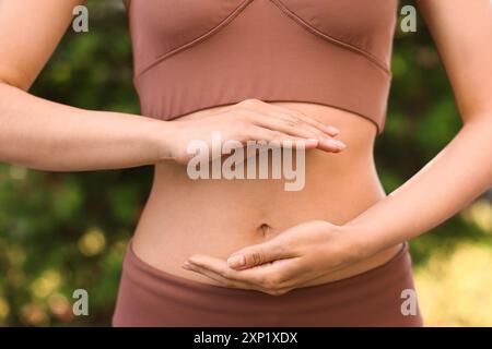 Digestione sana. Donna che tiene qualcosa vicino alla pancia all'aperto, primo piano Foto Stock