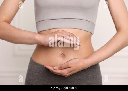 Digestione sana. Donna che tiene qualcosa vicino alla pancia dentro, primo piano Foto Stock