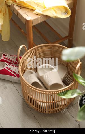 Cestino con pantofole per gli ospiti e scarpe da ginnastica all'ingresso di casa Foto Stock