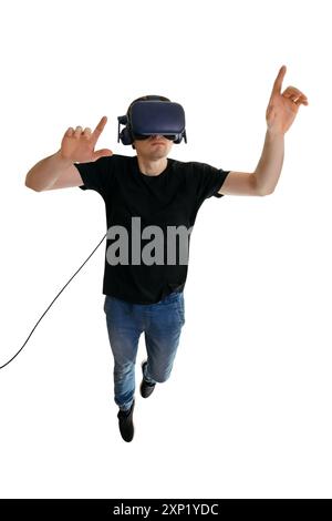 Un giovane calmo che indossa occhiali VR e punta in aria mentre vola su sfondo bianco. occhiali 3d. Concetto di intrattenimento innovativo Foto Stock