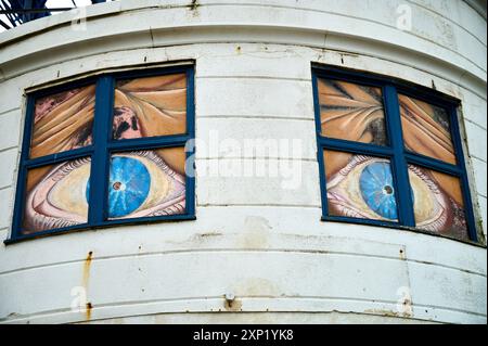 Grandi occhi malvagi che guardano fuori dalle finestre di sopra Foto Stock