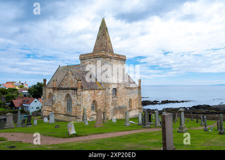 St Monans, Scozia, Regno Unito - 13 luglio 2024: L'antica chiesa di St Monans e cimitero con la sua caratteristica architettura ad arco e spier seduta prou Foto Stock