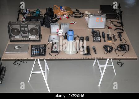 Un set completo di apparecchiature di registrazione audio visualizzato su un tavolo. Questa collezione comprende microfoni, cuffie, mixer audio, un megafono e altri dispositivi di registrazione essenziali adatti per la registrazione audio professionale e amatoriale. Foto Stock