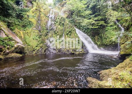 Un 'sentiero inferiore' conduce lungo un beck, con diverse piccole cascate e acqua bianca, terminando all'alta goccia della cascata Ceunant Mawr a Llanberis. Foto Stock