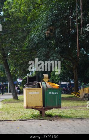 Cestini di spazzatura in spazi pubblici aperti nel centro della città di Malang che sembrano sporchi e pieni di spazzatura la mattina con le parole "Organik" e "Anorganik" Foto Stock