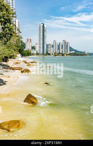 Una vista lungo la spiaggia di Tanjing Tokong a Penang, Malesia, con grattacieli alti e moderni, parte di un grattacielo cittadino sullo sfondo. Foto Stock