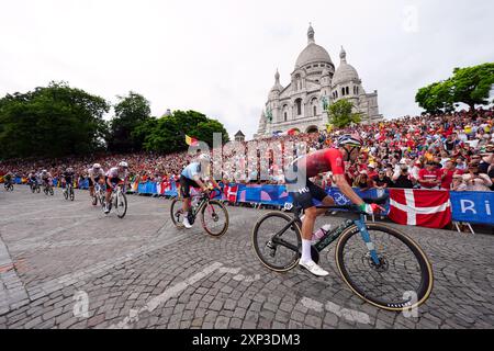 Il gruppo passa davanti alla Basilique du Sacre Coeur de Montmartre durante la gara ciclistica maschile dell'ottavo giorno dei Giochi Olimpici di Parigi del 2024 in Francia. Data foto: Sabato 3 agosto 2024. Foto Stock