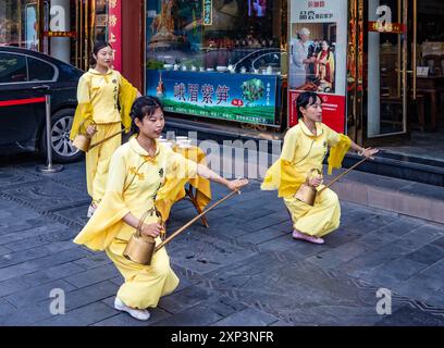 Giovani donne che ballano il tè di fronte a un negozio di tè lungo la strada storica di Qintai (琴台). Chengdu, Sichuan, Cina. Foto Stock